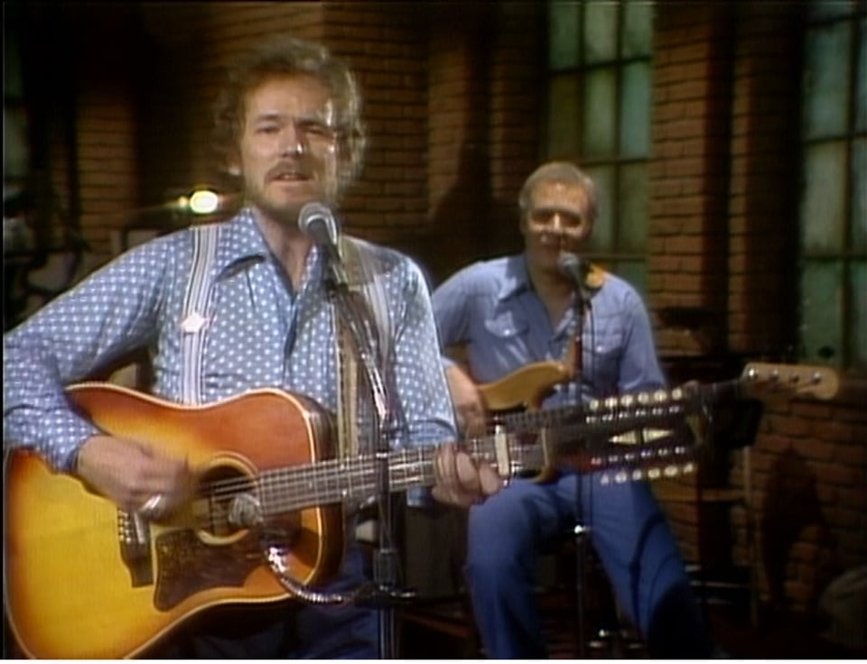 two men singing and playing an acoustic guitar
