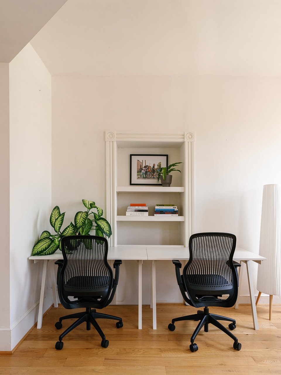 Two desks and desk chairs facing a built in bookshelf.