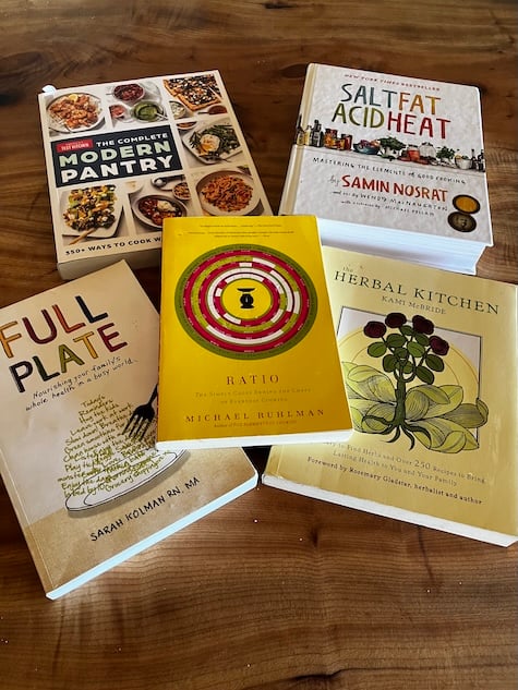 Image of five excellent books about cooking and stocking a pantry. The authors are America's Test Kitchen, Samin Nosrat, Sarah Kolman, Michael Ruhlman, and the local legend Kami McBride.