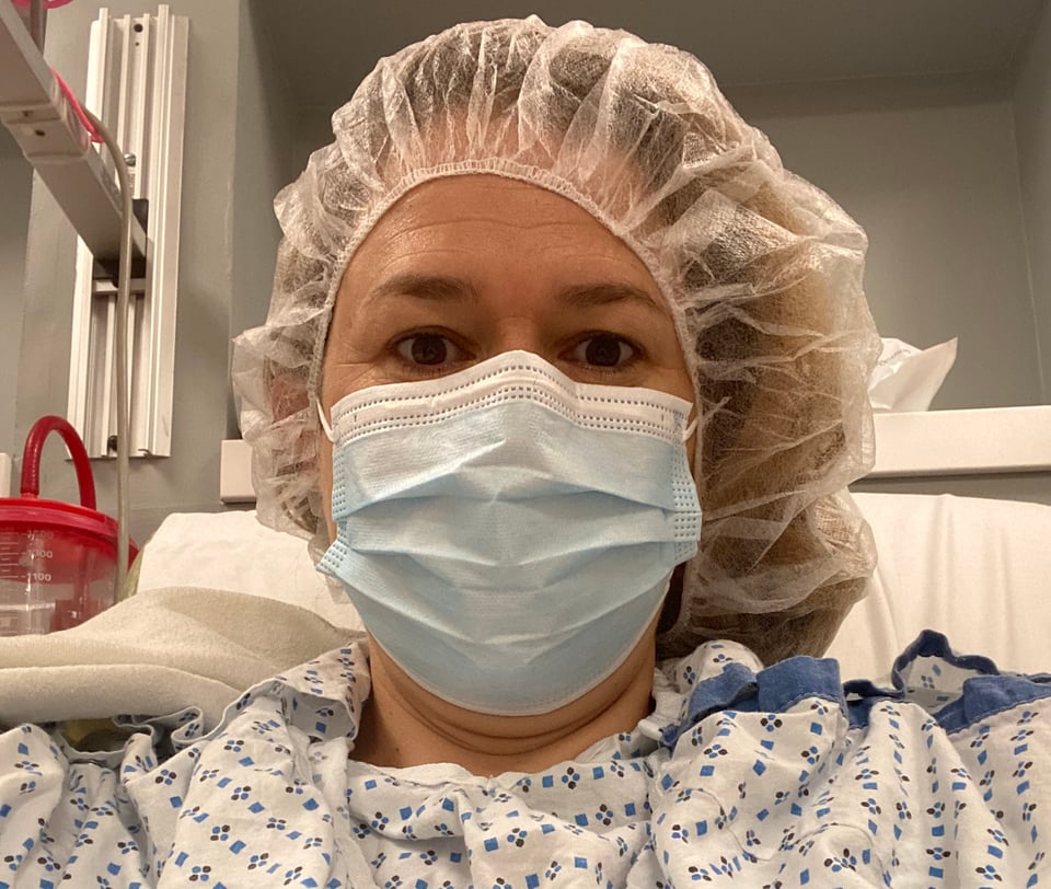 woman in surgical mask, cap, and gown at hospital
