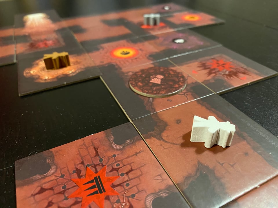 Three wooden meeples laying flat on square tiles forming a map of underground chambers