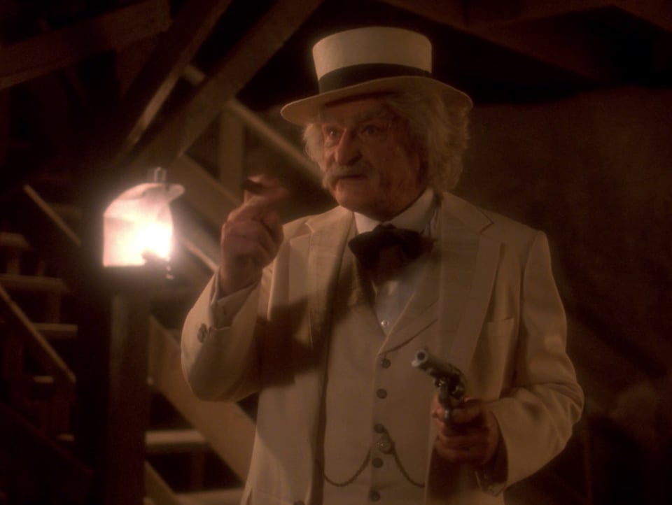Mark Twain (of all people) pointing a Colt 45 at crewmembers of the Enterprise-D. He is holding a gun in one hand, and a cigar in the other.