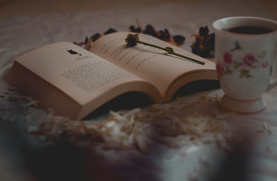 a book layers on a white table next to a mug of tea