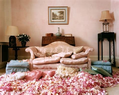 An empty room with a pink sofa surrounded by rose petals.