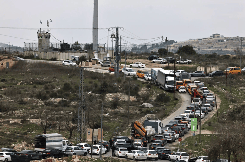 A large traffic jam on a winding road with a military tower in the distance