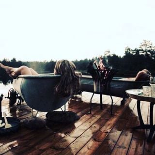 Two adults, each in their own bathtubs with a fire in between them.