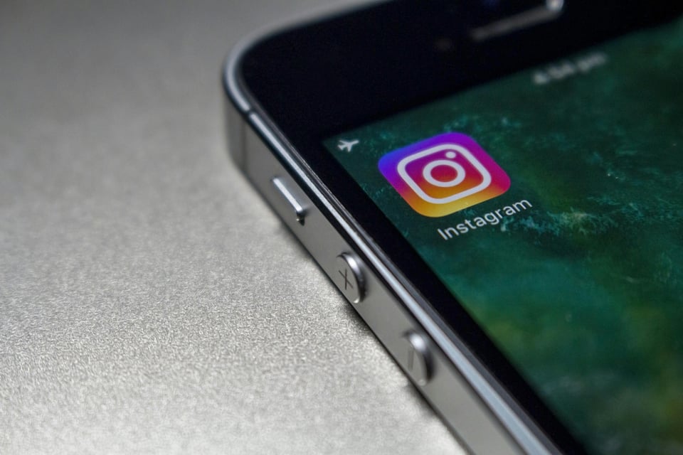 Close-up image of a cellphone that is on, showing off the Instagram logo on it specifically.