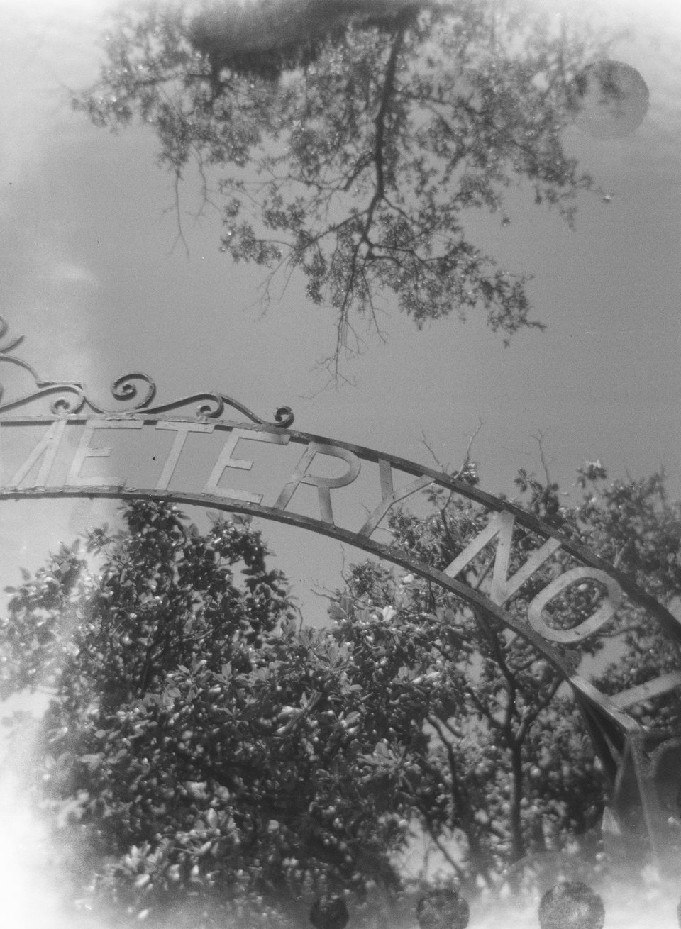 a black and white photo of a sign at a cemetary in New Orleans