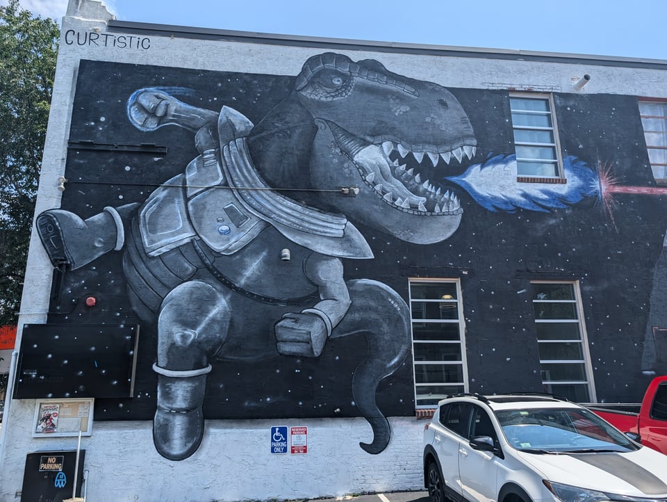 Street art shows a T-Rex in a spacesuit fighting with a breath weapon