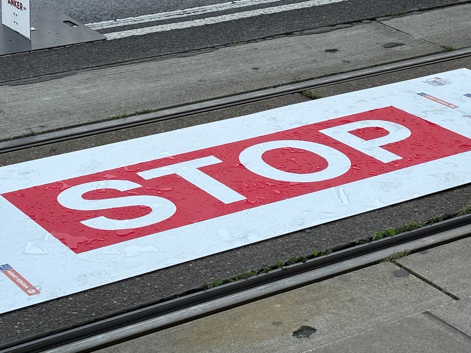 Tram tracks with a huge STOP sticker between them, with water splashed on the letters