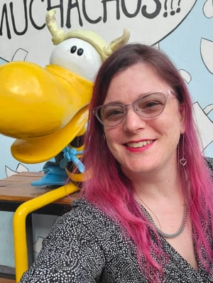 Meredith smiles next to a statue of a cartoon character who kind of looks like a horned version of Woodstock, from Peanuts.