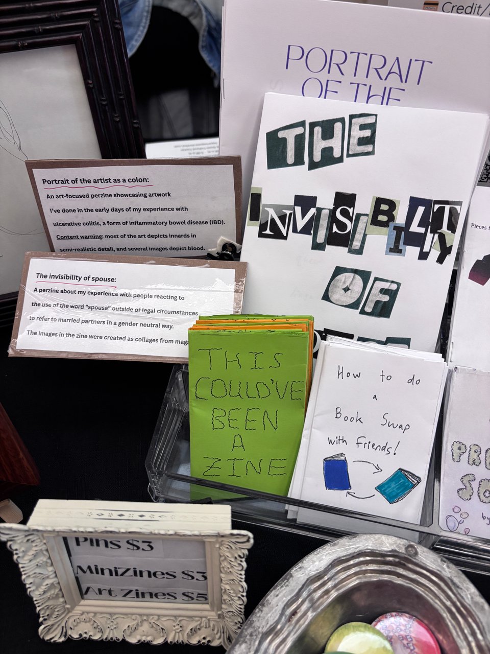 A stack of zines with two shelf talkers alongside two of them