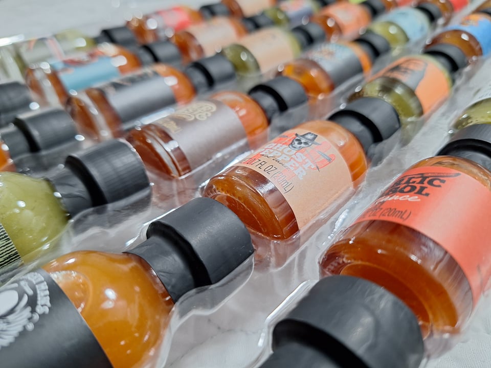 an array of many tiny sample bottles of different hot sauces, nestled in plastic packaging