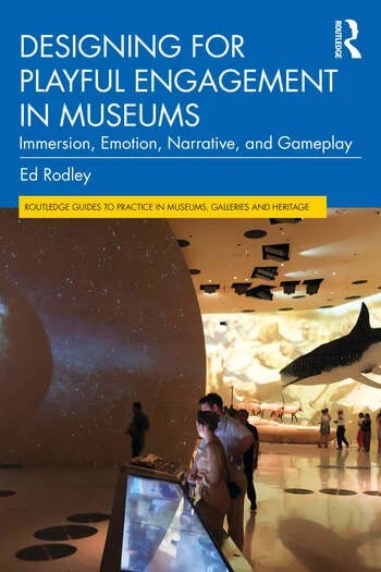 Image of Ed's book cover. The title of the book is displayed in white againsta bright blue background. Below it is a picture of a museum gallery full of objects and interactives being used by people.