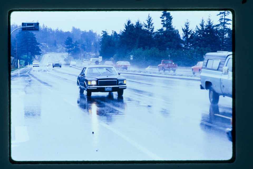 A car travels on a wet paved highway
