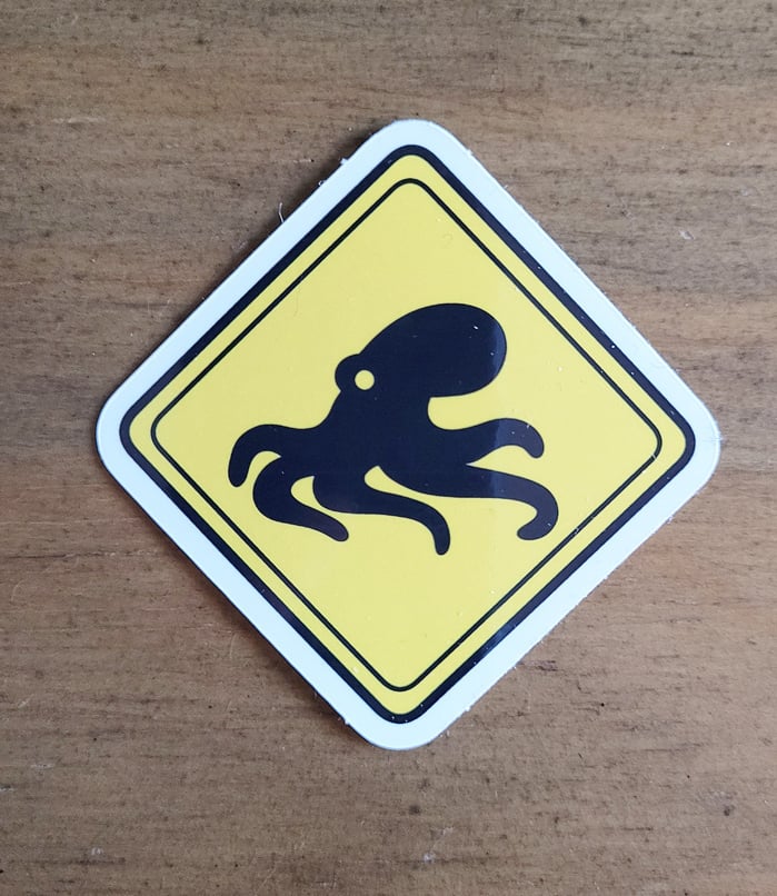 one of those yellow diamond shaped “animal crossing” signs, except this one has a picture of an octopus crawling along the ground.