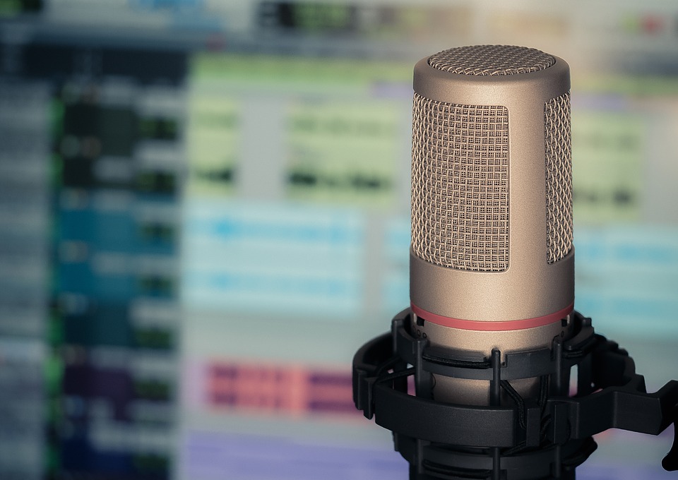 A picture of a microphone with a blurry audio editing application in the background.