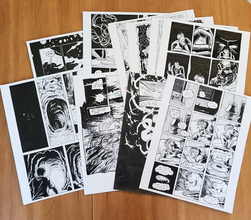 A photograph of several original art pages from Look Straight Ahead, Elaine's first graphic novel, fanned out on a table.
