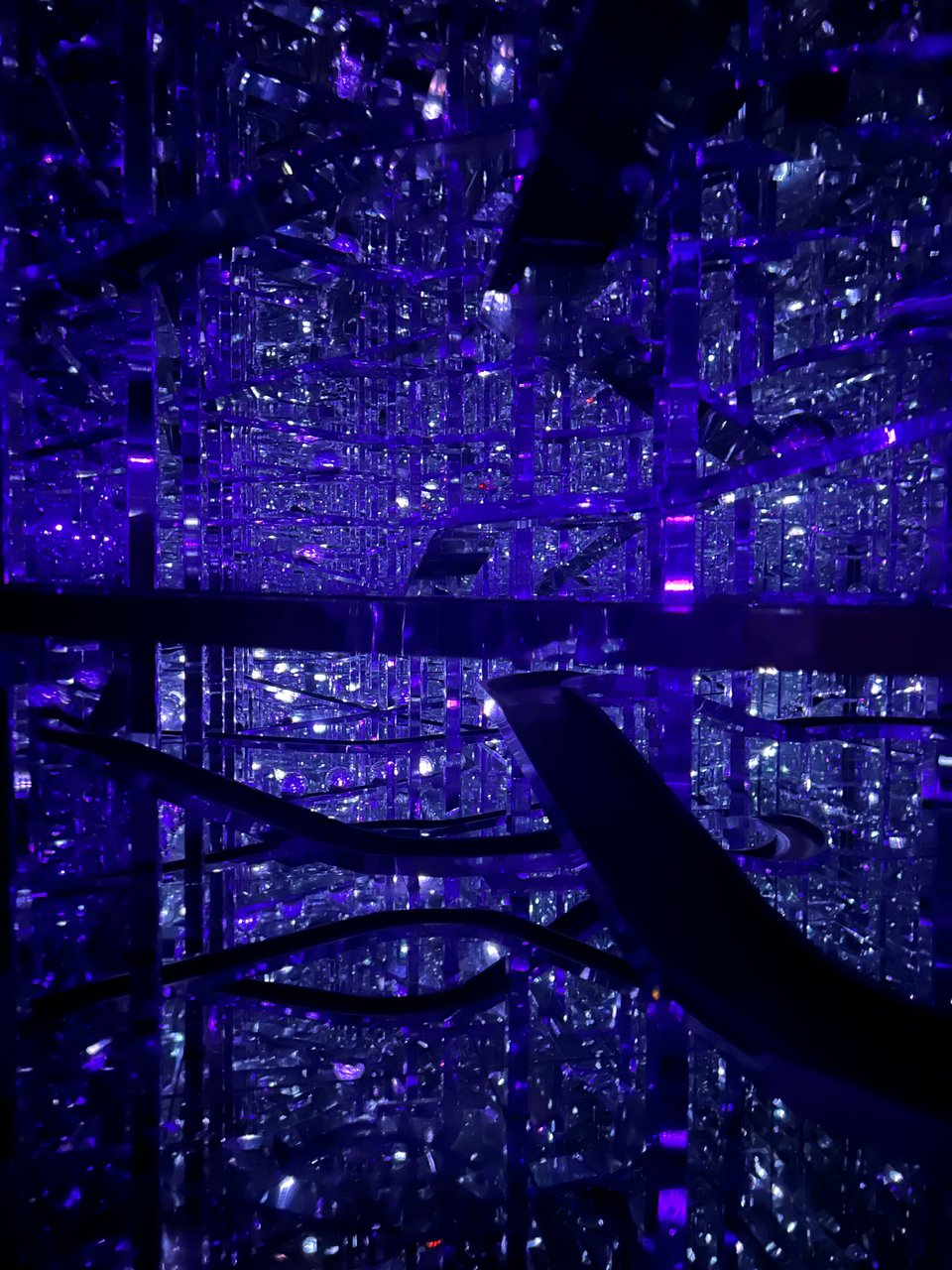 lights reflecting off of metal ramps, spheres and off mirrors create a mysterious, starlike effect in a digital art museum.