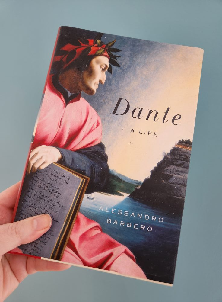 My hand holding a hardcover of Dante: A Life by Alessandro Barbero. The cover has an illustration of the poet.