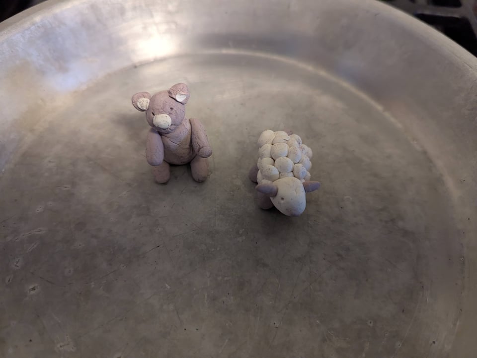 Clay models of a teddy bear and sheep made with lots of slightly squished white spheres