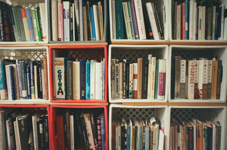 [Bookshelves built of milk crates on their sides. The spines of the books fit snuggly into the square boxes, which are stacked neatly in rows and columns.]