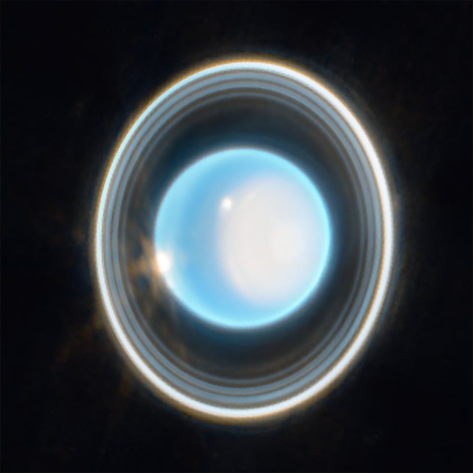 Uranus, as seen from James Web Telescope; a bright blue orb with rings of light around it