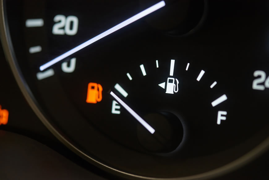 A car dashboard fuel gauge pointing to empty