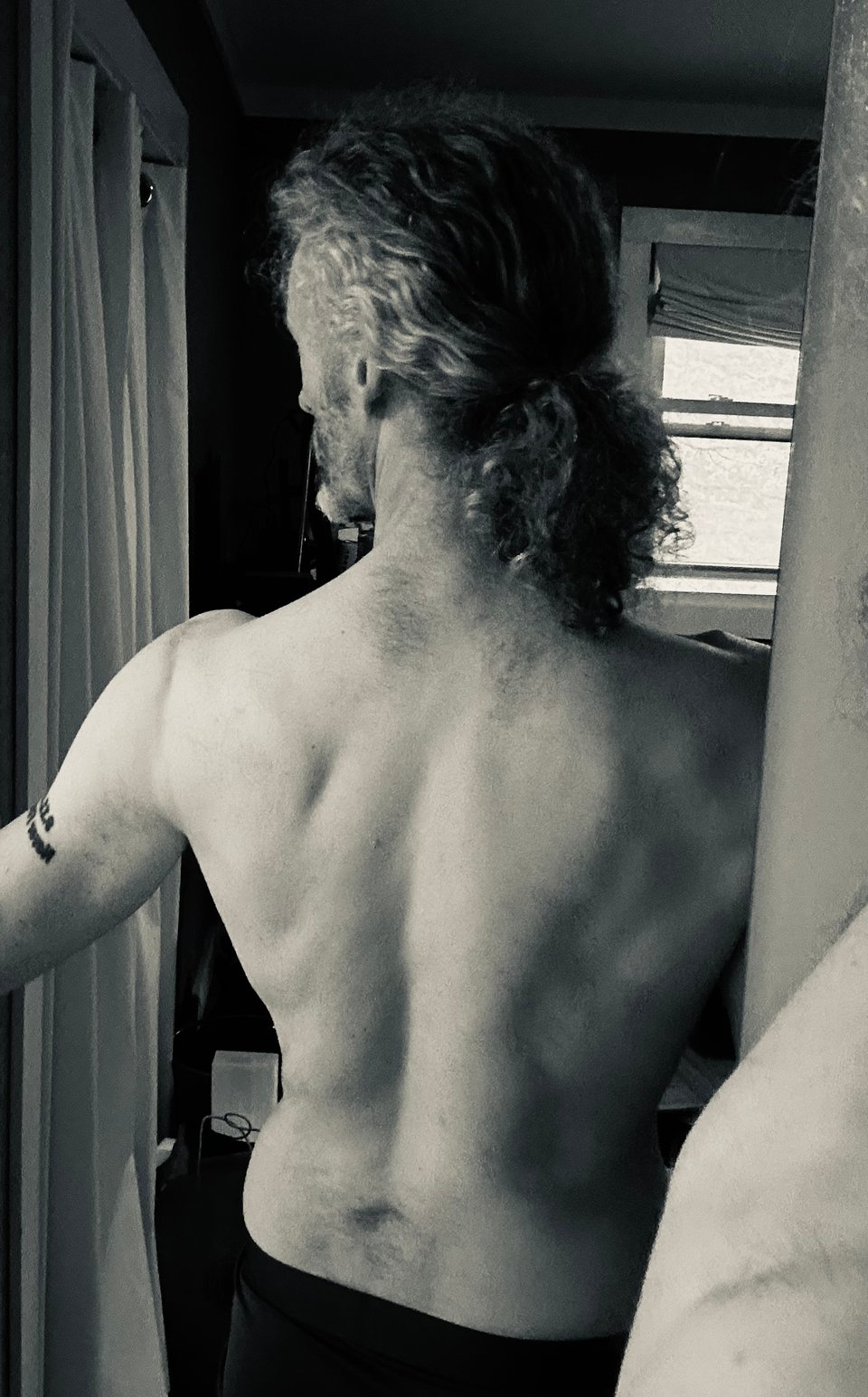 B/W photo in mirror of white man with kinda muscular back, but he's hairy so it's gross