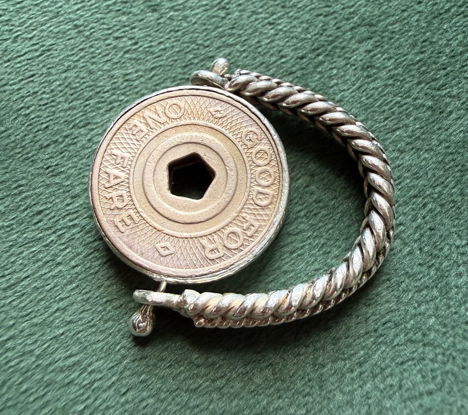 NYC subway token set in a braided silver ring against green background