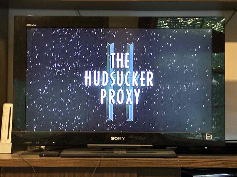 A photo of my television, which in this instant displays the title of the movie The Hudsucker Proxy. There is snow in the bathroom.