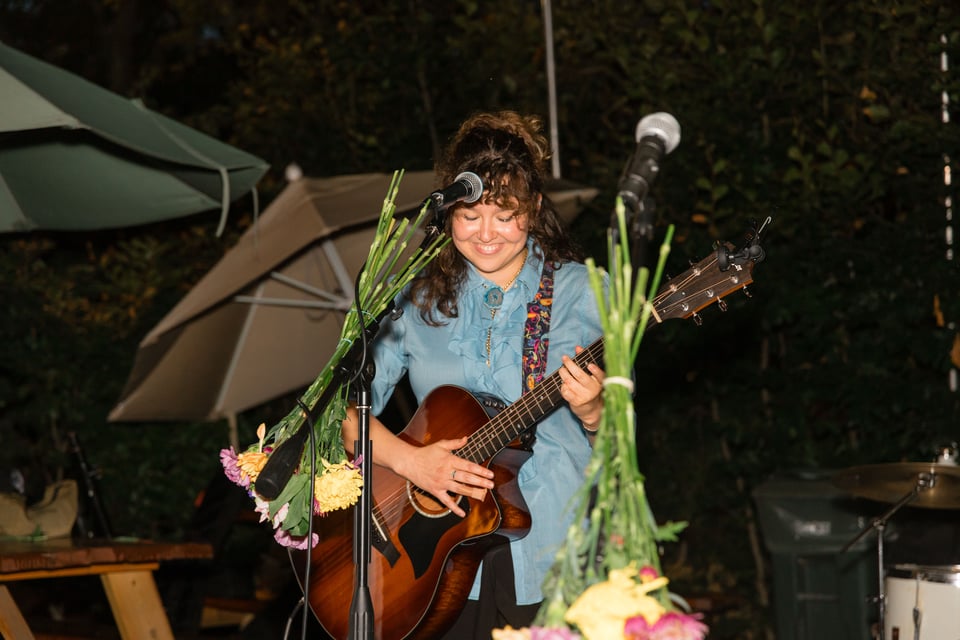 Ellie Fern smiles at the end of her set, holding a guitar