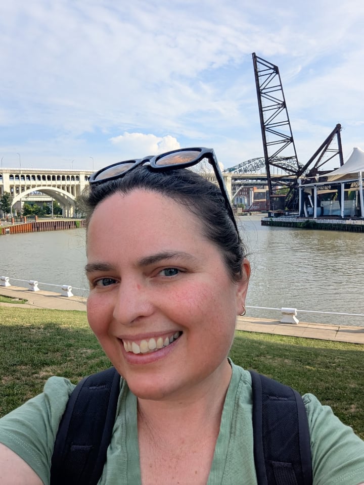 The writer with backpack and sunglasses. A bend of the Cuyahoga River is visible in the background.