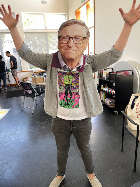 Me in a Combo Chimbita shirt wearing an oversized Bill Gates mask, both arms raised like Godzilla