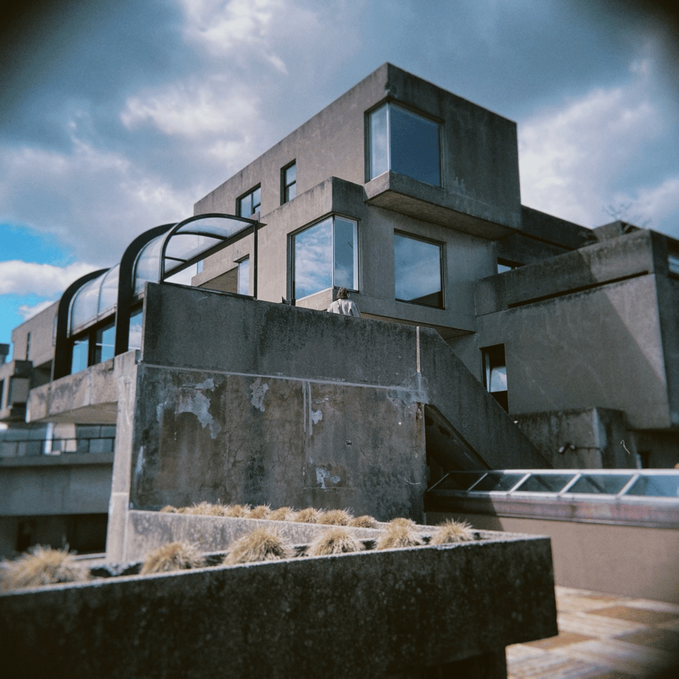 The top cubes of a brutalist concrete apartment building, with curved glass barrier.