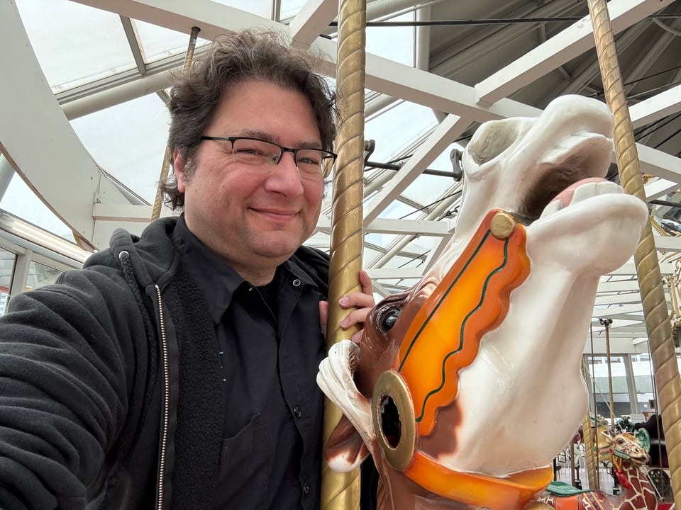 Seg taking a selfie while riding a horse on the LeRoy King Carousel.