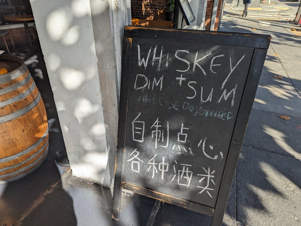 A billboard says WHISKEY AND DIM SUM: WHAT ELSE DO YOU NEED