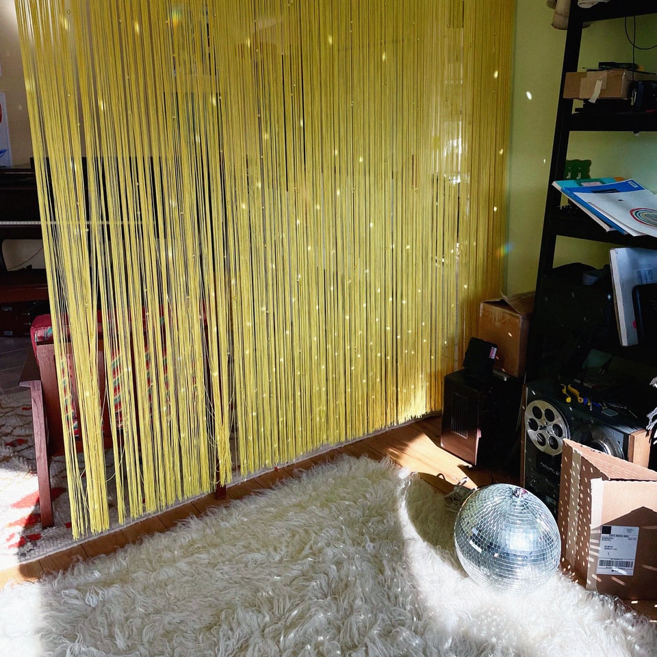 a disco ball on a white rug shines in a room with a yellow curtain