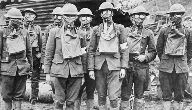 A group of 8 WWI era soldiers wearing gas masks