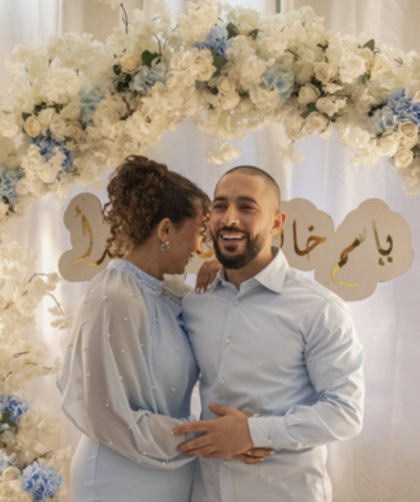 A young man (Aboud) in a dress shirt and a woman in a dress (Majdal), both in light blue in a light embrace