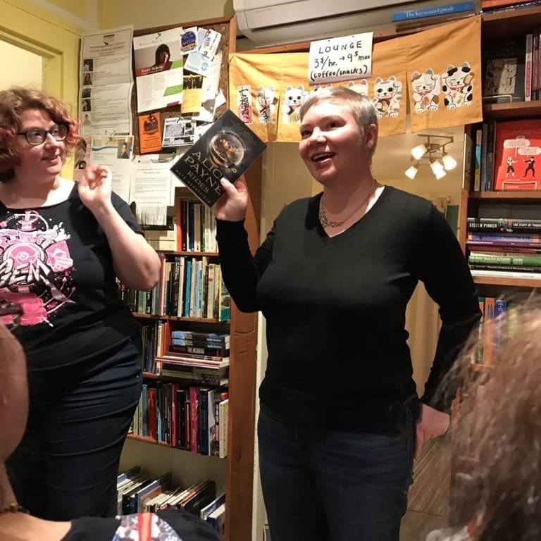 Kate holding a copy of Alice Payne Arrives and declaiming.