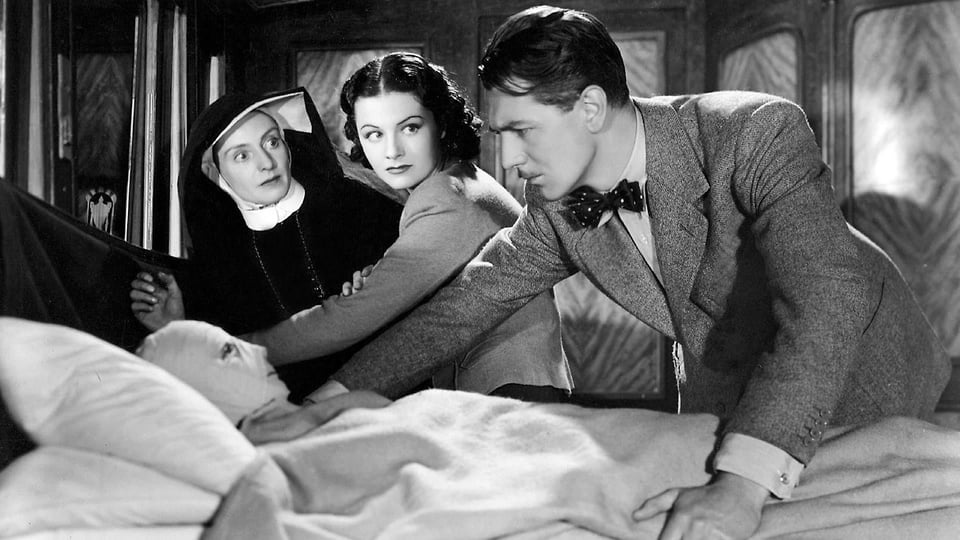 A scene from The Lady Vanishes where the nun and the two protagonists check the "binded" men.