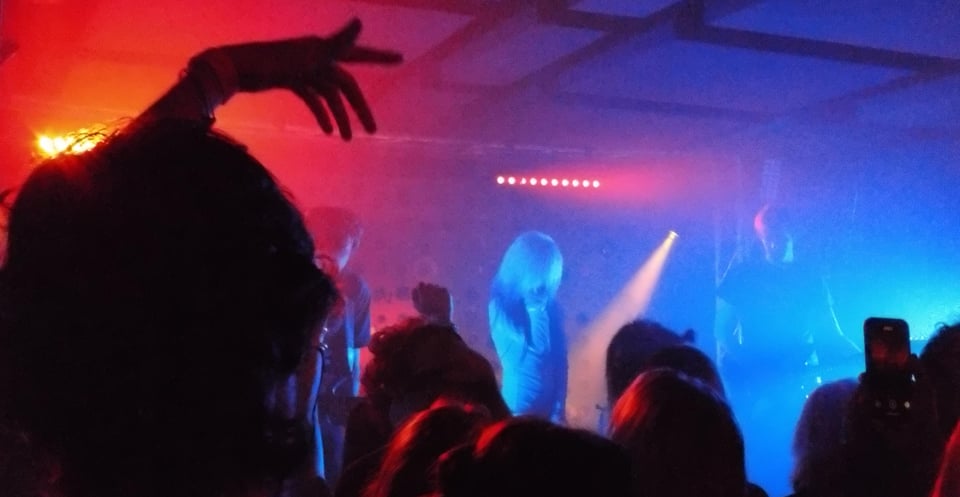 Grungy photo of daine performing, all red and blue and whatnot