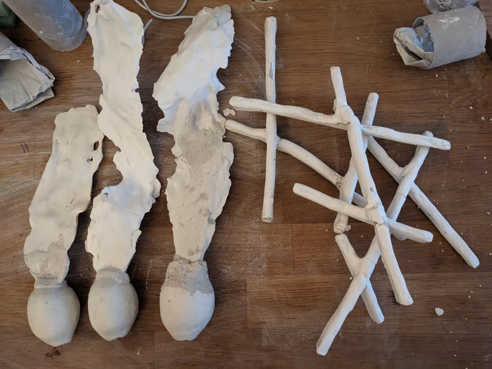 Plaster sculpture parts in the shape of kelp bladders with blades, and stems, on a wooden surface