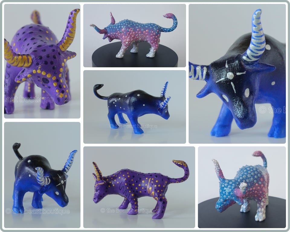 A collage showing three bull figurines with their heads lowered from multiple angles, all painted in different colors. One bull is painted iris purple, decorated with dark purple and gold polka dots and squiggly lines following the contours of its form. The next bull is painted in a dark blue gradient, nearly black along its back, and lighter near the feet. It has silver horns and eyes, a starburst on its forehead, and dots loosely representing the constellation 'Taurus' on its sides. Last, the bull is painted blue, pink, and white, blue on its back, pink on its middle, and white on its belly and legs. It's decorated with light blue and medium blue dots accenting the blue portion of the body, Light pink and medium pink dots on the pink portion, and white and silver dots on the white areas.

the image is watermarked  with the shop name, the beast boutique.