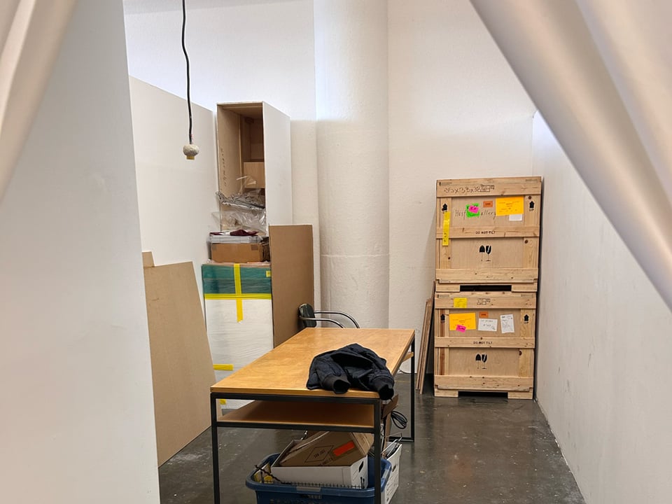 New art studio. Someone else's clutter is still in it. Table. Crates. Lotta white walls though.