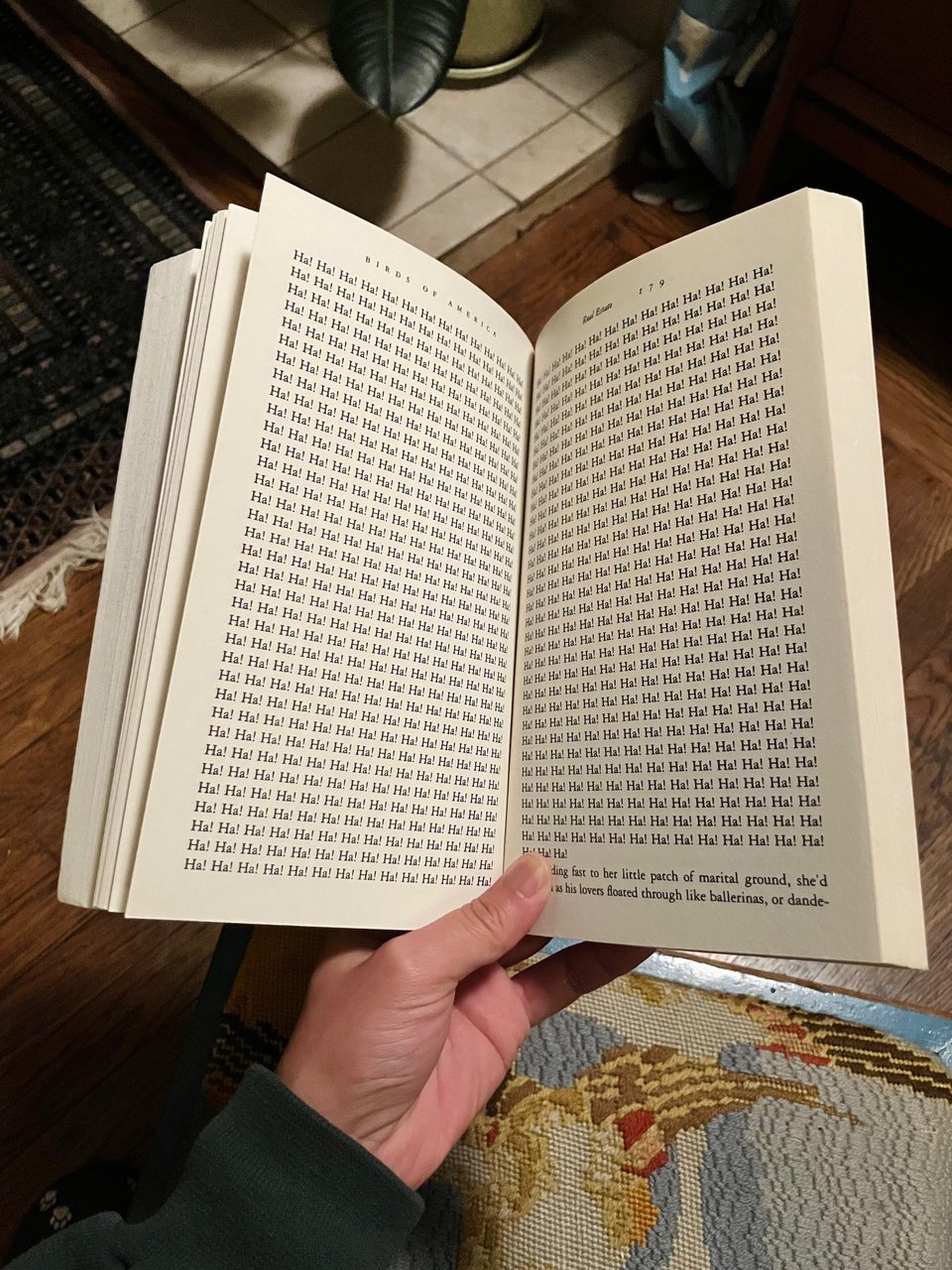 Photo of an open book featuring the text "Ha! Ha!" repeated across two pages. From the short story "Real Estate" from the collection "Birds of America" by Lorrie Moore.