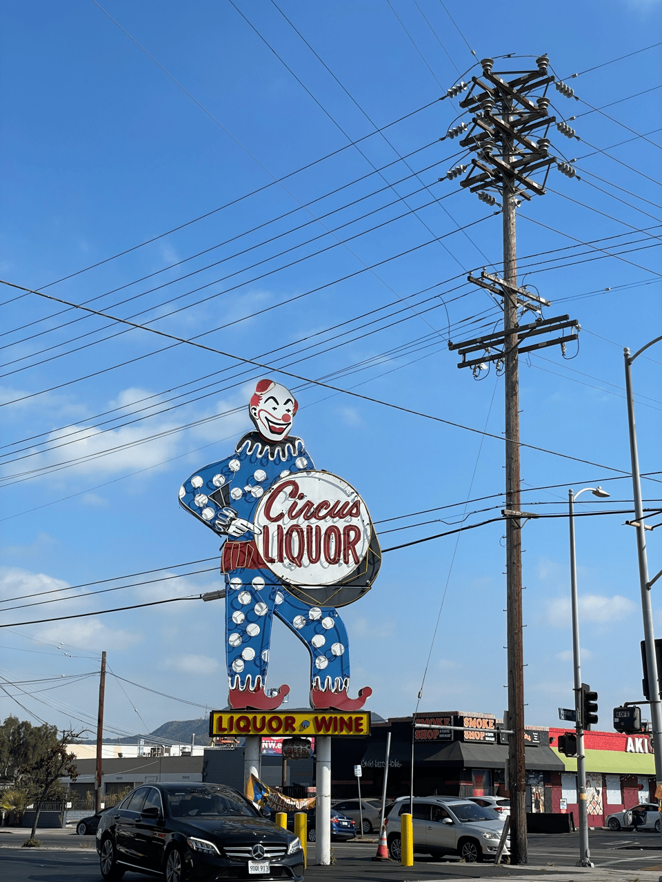 A large neon sign of a clown pointing at a drum that reads Circus Liquor