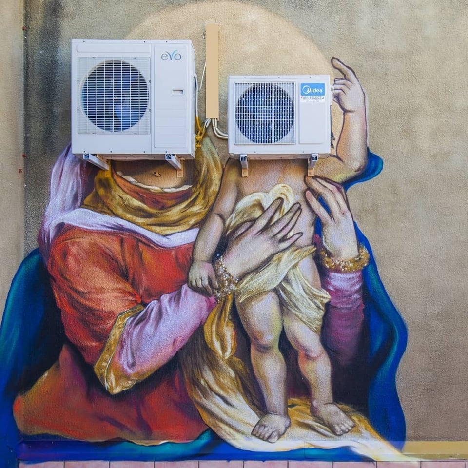 A wall mural painted in a Renaissance (or maybe Baroque?) style of a Virgin Mary holding a Baby Jesus but their faces are air conditioning condenser units