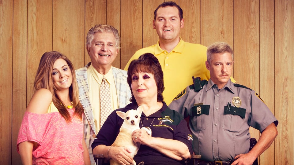 a group of five people and a dog posing for a picture in front of a paneled wall